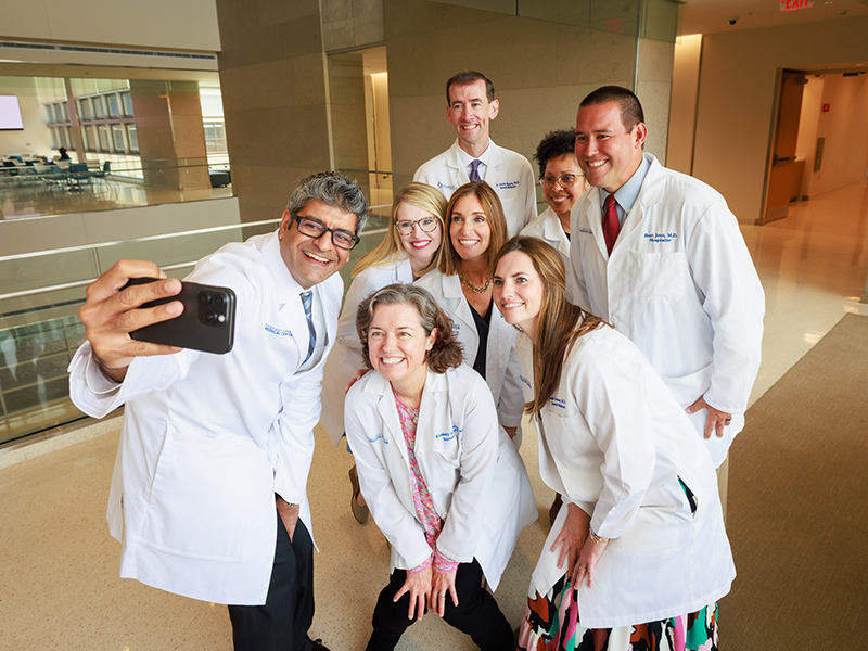 Eight program leaders taking a selfie inside the School of Medicine.